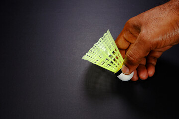 A badminton rocket holding hand black background close-up view copy space, A shuttlecock racket...
