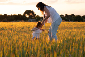 Tender Moment Between Mother and Daughter in a Wheat Field at Sunse