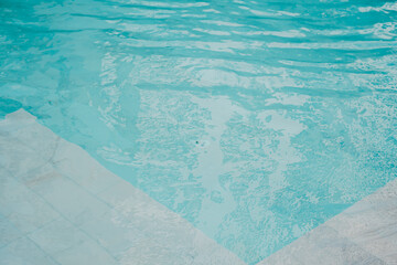 Swimming Pool concept. Tranquil Water Surface in Swimming Pool with Gentle Ripples and Sunlight Reflection on Calm Aquatic Scene