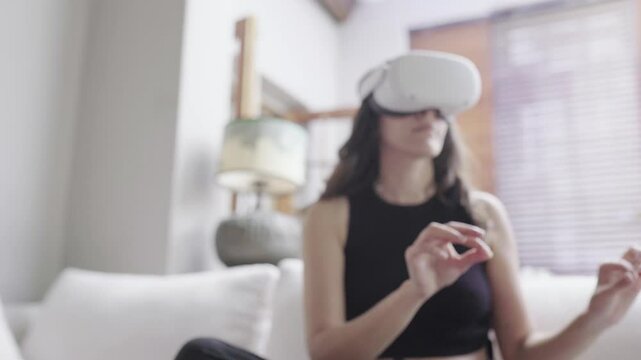 A Woman immersed in virtual reality at home with VR headset and gesture control. She wears a VR headset and interacts with virtual content using hand gestures - Powered by Adobe