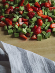 Vertical Flat Lay of Chopped Rhubarb and Strawberries for Galette Filling and Dish Towel on Wooden Table