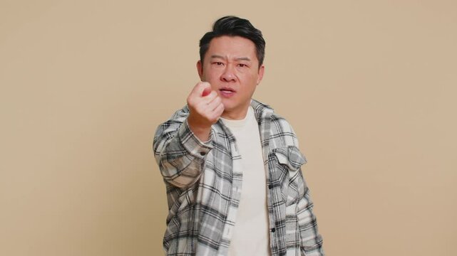 Angry aggressive Asian middle-aged man showing fig negative gesture, you dont get it anyway. Rapacious, avaricious, acquisitive. Body language. Refusal fig sign. Greedy frustrated mature Chinese guy.