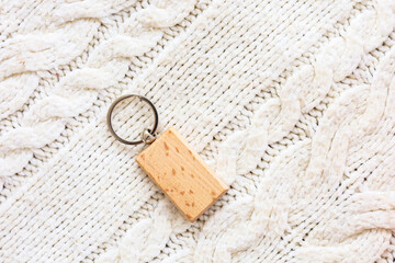 Keychain with wooden rectangular charm resting on knit fabric background