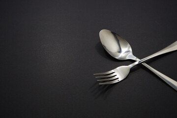 spoon and fork set together on black background with copy space