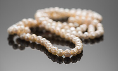 Pearl necklace over black background, close up. Beautiful Natural pearls beads, elegant accessories macro shot. 