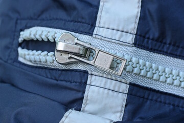one white closed metal plastic zip on the pocket on a blue synthetic fabric © butus