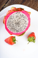 Close up of Dragon fruit and strawberries on white plate.