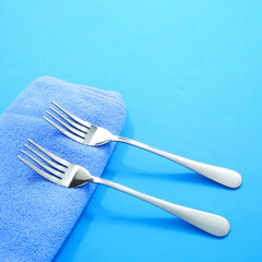 fork set together with blue cotton towel with blue background close-up view, Food concept...