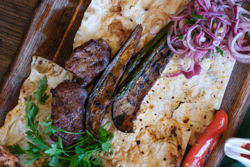 Grilled meats and vegetables served on flatbread in a rustic setting