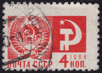 A stamp printed in the former USSR in 1966 features State Emblem of the Soviet Union and communist...