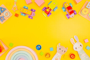 Toys for toddlers on yellow background. Wooden educational toys and soft plush toys for children. Top view, flat lay, copy space for text
