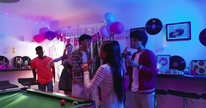 Birthday celebration driving diverse friends playing pool in party room dancing under disco ball