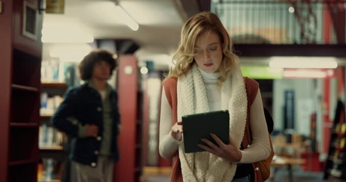 Woman, tablet and walking in library, student and online reading with social media. People, scholarship or knowledge with tech, network or learning with digital app, email or college with connection - Powered by Adobe