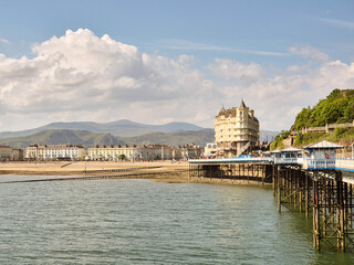 Victorian pier and hotel in Llandudno in Wales on a sunny day with mountains in the background