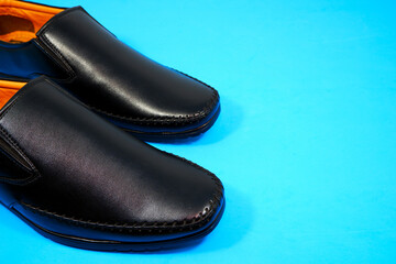 formal black shoes closeup shot on blue background 