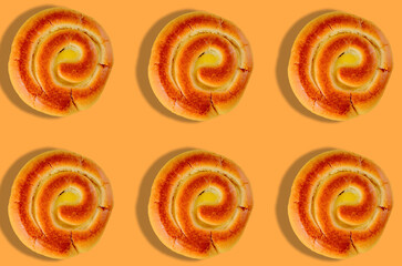Sweet spiral buns in seamless pattern on orange background