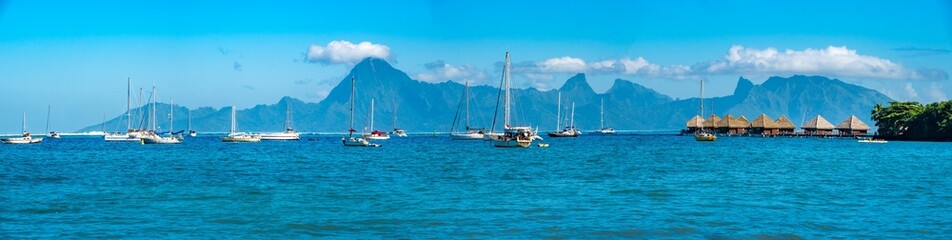 Fototapeta premium Panoramic view of the Papeete marina with the stunning island of Moorea in the background, Tahiti, Society Islands, French Polynesia, South Pacific. On the right, the iconic bungalows on stilts