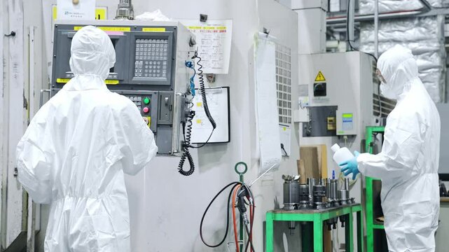 工場で機械を操作する防塵服を着た男性作業員