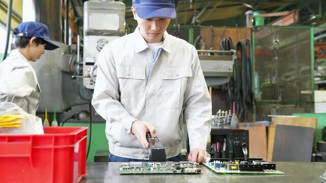 工場でハンディターミナルを使って製品を検査する男性作業員