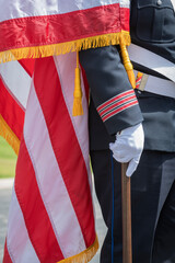 Person wearing a formal uniform with a white belt and gloves, holding a pole.
