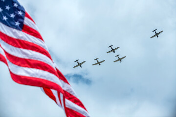 Planes fly over a Memorial Day event with the United States flag in the foreground