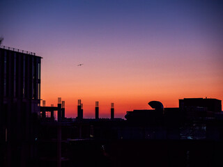 Silhouette of a modern construction site and purple and orange sun rise sky. Calm and relaxing mood.