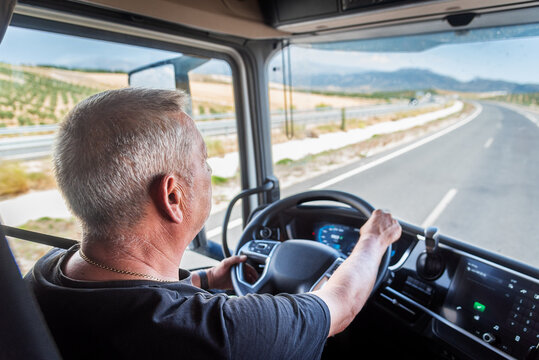 Aging truck driver behind the wheel, experienced but with slower reflexes, highlighting road safety issues.