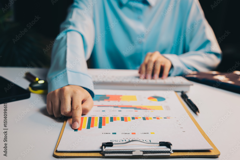 Poster business analysis with charts and graphs at desk with keyboard and stationery in office setting