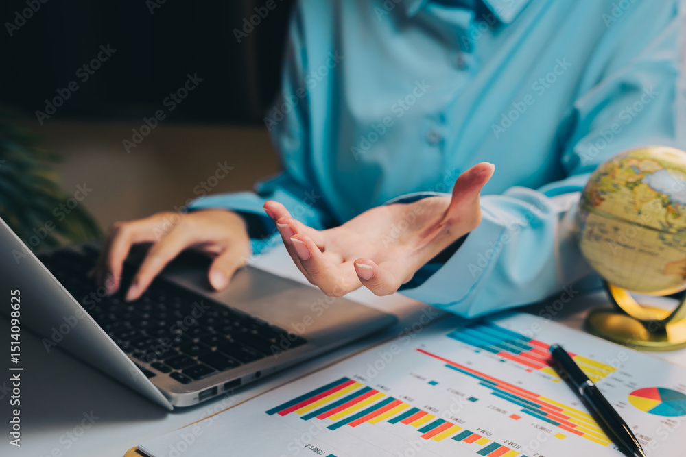 Aufkleber person engaged in online discussion while using laptop surrounded by charts and a globe on a workspa