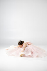 A young girl in a flowing pink dress poses playfully against a plain background.