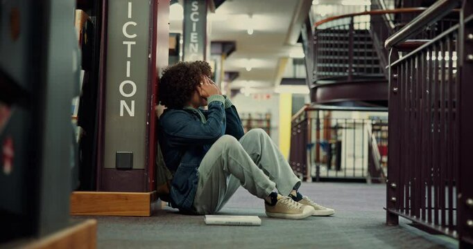 Stress, frustrated student and man in library for test fail, depression and study fatigue in university. College, sad and unhappy person overwhelmed with assignment deadline, exam pressure or burnout