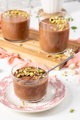 Three individual servings of chocolate mousse topped with chopped pistachios