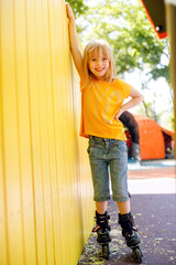 Little girl roller skating against yellow background
