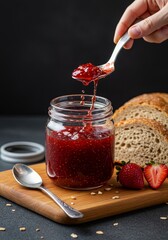 Close Up Photo of Strawberry Jam with Hand Slicing Bread on Table