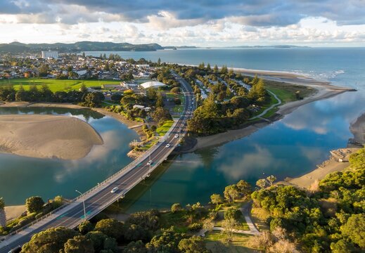 Aerial view of Orewa, Auckland, New Zealand, showcasing the estuary where the Orewa River meets the sea. The bridge connects the town, highlighting coastal living and natural beauty.