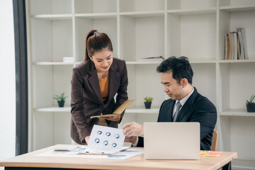 Business men and women discussing charts and graphs showing results of successful teamwork using laptops. Business strategy planning and brainstorming.