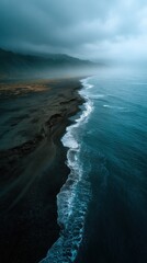 Fototapeta premium Coastal Serenity: Aerial perspective of a dramatic coastline where dark sand meets the powerful ocean under a moody sky, showcasing the raw, untamed beauty of the natural world. 