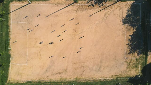 Aerial drone view of amateur athletes playing soccer on a sand field, a common activity in the brazilian countryside