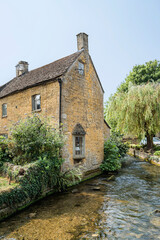 Bourton-on-the-Water, Cheltenham, UK - August 2025 : stone house by the river Windrush 