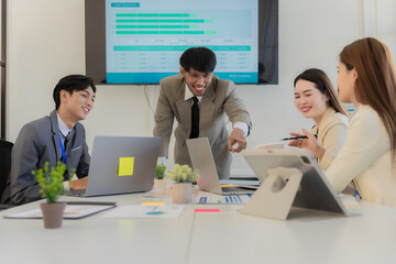 A team of professionals are reviewing financial charts, working together to analyze data for strategic planning and decision-making processes during a meeting in an office conference room.