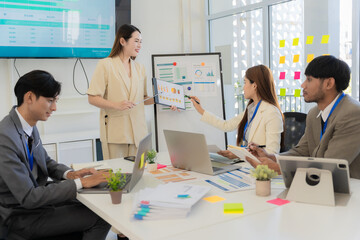 A team of professionals are reviewing financial charts, working together to analyze data for strategic planning and decision-making processes during a meeting in an office conference room.
