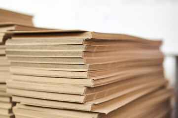 Stacks of thick paperboard ready for transformation into sturdy cardboard boxes within a bustling manufacturing facility