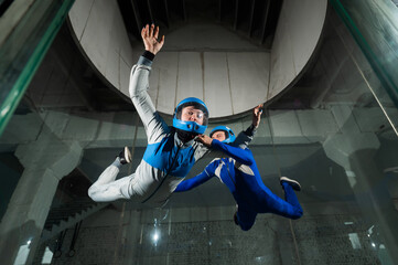 A male instructor teaches a woman how to fly in a wind tunnel. Free fall simulator.