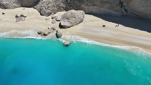 A side aerial view of a beautiful beach with blue sea and tourists enjoying their beach holiday.
