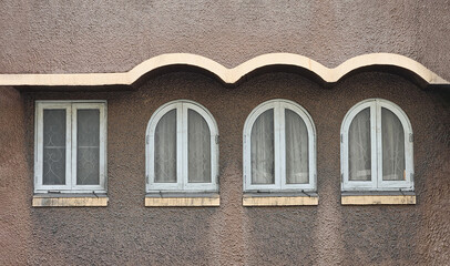 Four white wooden windows on brown or red rough wall. Some of them shape difference but same object and Different but not divided. Old structure or building, Exterior design and vintage style.