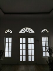 Gothic church window with ancient arched stone detail and blue glass, light streaming into an old house