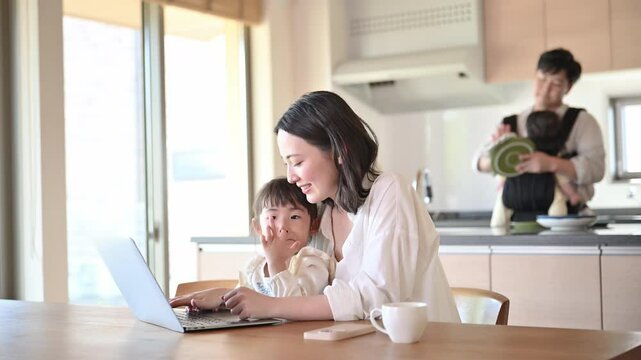 自宅のリビングで仕事をするママと家事をするパパ　リモートワーク、共働きや主夫のイメージ動画