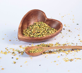 Crushed pistachio nuts in wooden bowl and heart-shaped spoon for cooking. Environmentally friendly product and health.