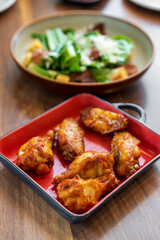 Roasted grilled chicken legs or baked chicken wings new orleans and barbecue or bbq in square plate with vegetables salad on wooden table for protein food or cuisine to lunch or dinner in restaurant
