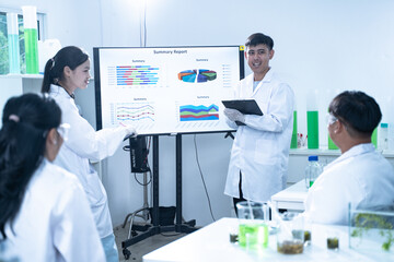 In the laboratory, a group of researchers meets to report their findings, discussing their work and...